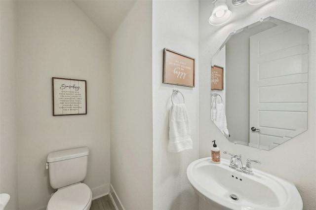 bathroom with hardwood / wood-style flooring, toilet, sink, and vaulted ceiling