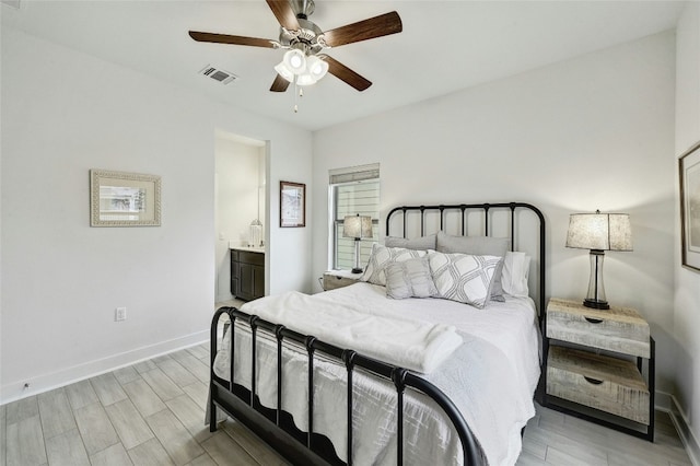 bedroom featuring ceiling fan, ensuite bath, and light wood-type flooring