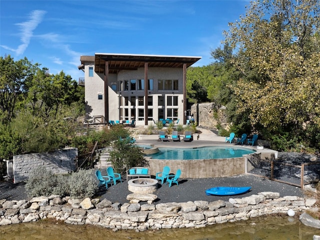 back of house with a fire pit, a patio, and a water view