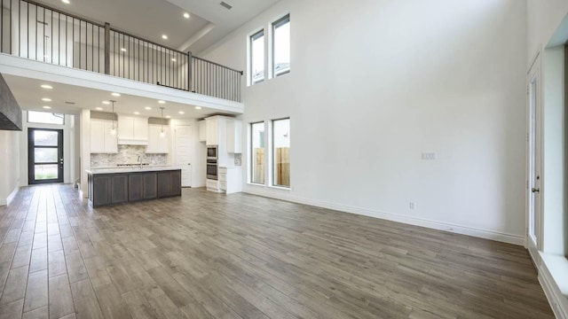 220 La Venta Loop, Liberty Hill, TX 78642 - unfurnished living room with wood finished floors, a towering ceiling, and recessed lighting