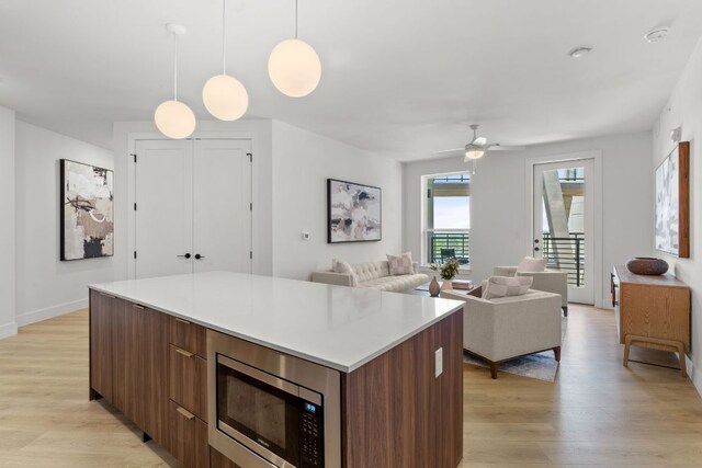 1701 Simond Ave Unit 546, Austin, TX 78723 - kitchen featuring stainless steel microwave, a kitchen island, modern cabinets, and light wood-style flooring