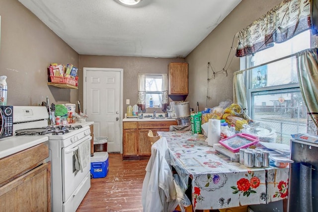 kitchen featuring white range with gas cooktop, sink, hardwood / wood-style flooring, and a textured ceiling