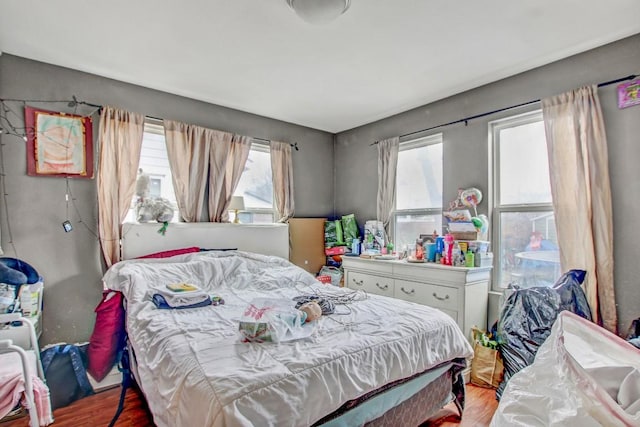 bedroom with multiple windows and light hardwood / wood-style flooring