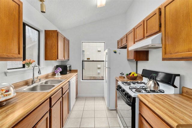 kitchen featuring lofted ceiling, sink, light tile patterned floors, white dishwasher, and gas range oven