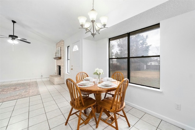 dining area featuring lofted ceiling, light tile patterned floors, a large fireplace, a textured ceiling, and ceiling fan with notable chandelier