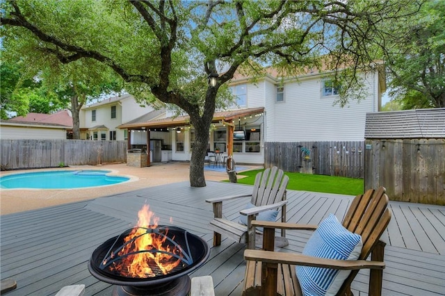 view of pool with a wooden deck and an outdoor fire pit