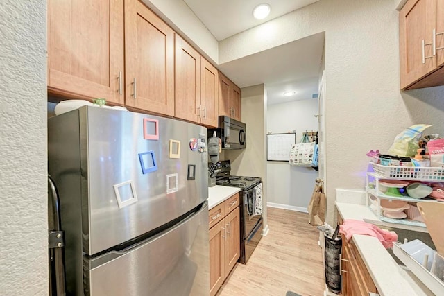 kitchen with light hardwood / wood-style flooring and black appliances