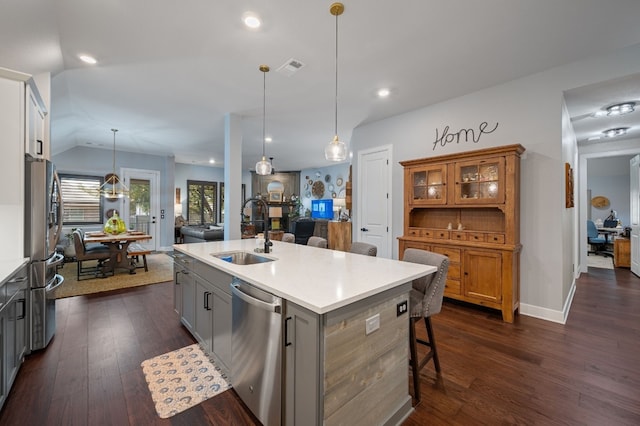 kitchen with gray cabinets, appliances with stainless steel finishes, sink, hanging light fixtures, and a kitchen island with sink