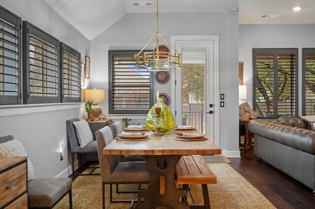 dining space with an inviting chandelier, vaulted ceiling, and dark hardwood / wood-style floors