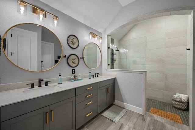 bathroom with lofted ceiling, vanity, hardwood / wood-style flooring, and tiled shower