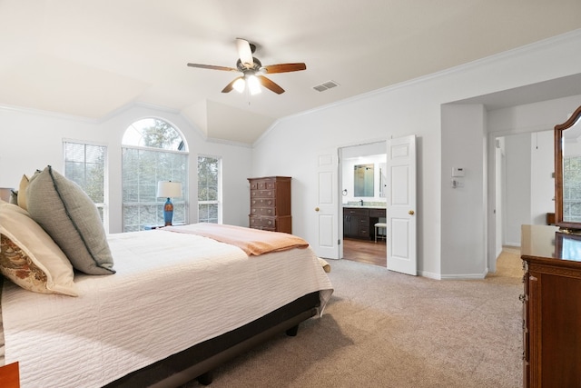 bedroom featuring vaulted ceiling, ensuite bathroom, light colored carpet, ceiling fan, and crown molding