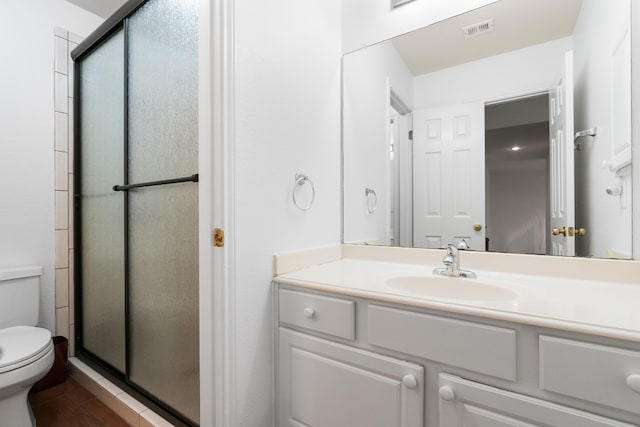 bathroom with vanity, a shower with door, and toilet