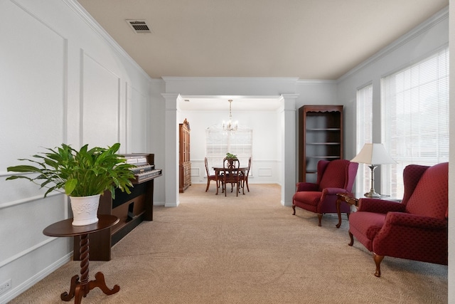 living area featuring ornate columns, crown molding, and light carpet