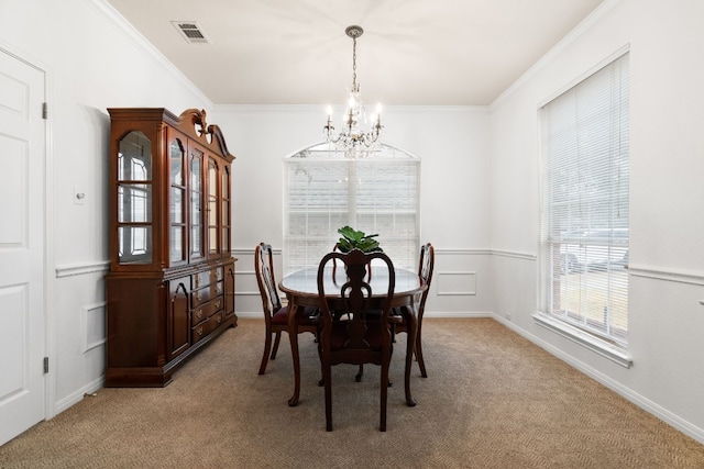 carpeted dining room with ornamental molding and a chandelier