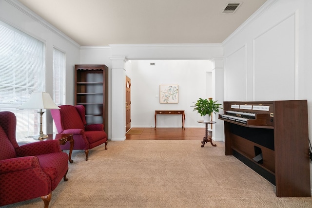 sitting room featuring crown molding, light carpet, and ornate columns