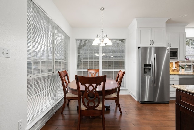 dining space with dark hardwood / wood-style flooring and an inviting chandelier