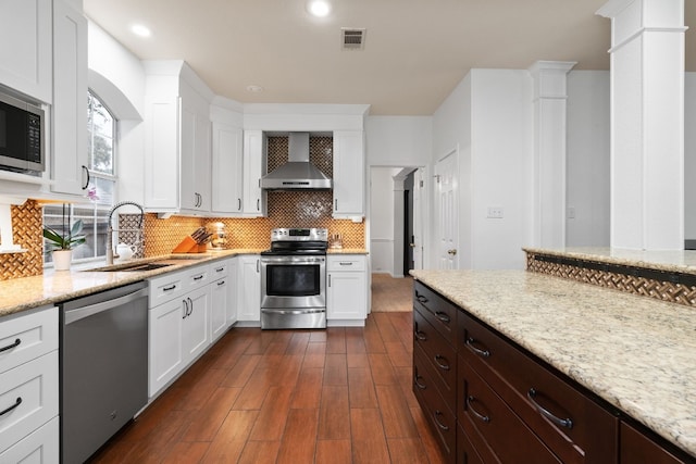 kitchen featuring white cabinets, stainless steel appliances, sink, and wall chimney range hood