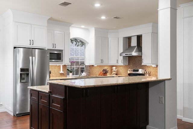 kitchen featuring tasteful backsplash, wall chimney range hood, stainless steel appliances, and sink