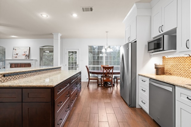 kitchen featuring white cabinetry, backsplash, decorative light fixtures, and stainless steel appliances