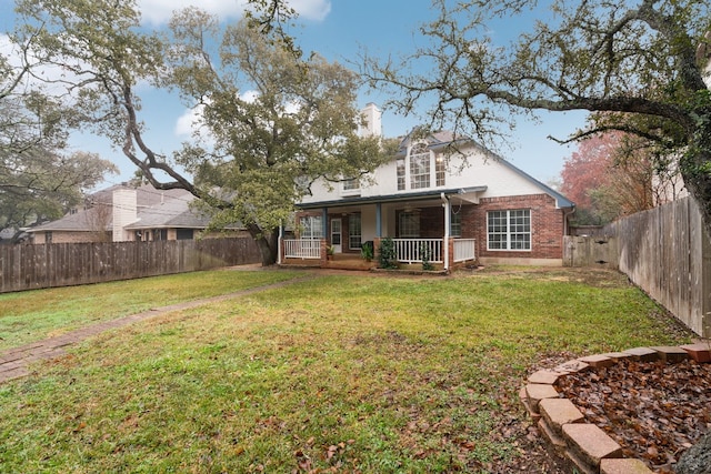 rear view of house featuring covered porch and a lawn