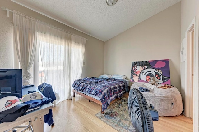 bedroom featuring vaulted ceiling, hardwood / wood-style floors, and a textured ceiling