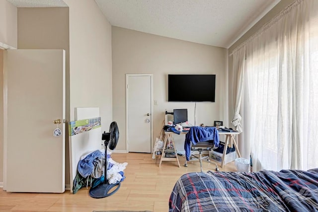 bedroom featuring multiple windows, lofted ceiling, hardwood / wood-style floors, and a textured ceiling