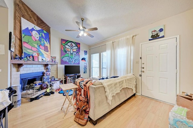 living room with ceiling fan, hardwood / wood-style flooring, a fireplace, and a textured ceiling