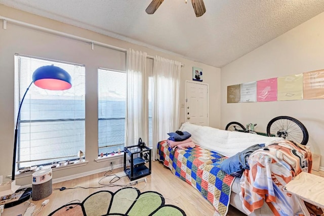 bedroom featuring ceiling fan, vaulted ceiling, light hardwood / wood-style flooring, and a textured ceiling