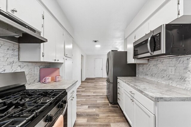 803 N 19th St, Copperas Cove, TX 76522 - kitchen with appliances with stainless steel finishes, under cabinet range hood, white cabinetry, light countertops, and light wood-type flooring