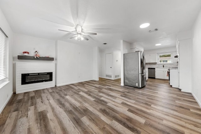 803 N 19th St, Copperas Cove, TX 76522 - unfurnished living room featuring wood finished floors, a ceiling fan, a glass covered fireplace, and baseboards