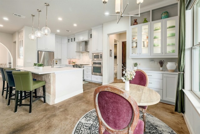 kitchen featuring visible vents, appliances with stainless steel finishes, hanging light fixtures, light countertops, and wall chimney range hood