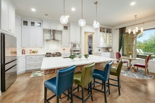 kitchen featuring stainless steel appliances, light countertops, white cabinetry, concrete floors, and wall chimney exhaust hood