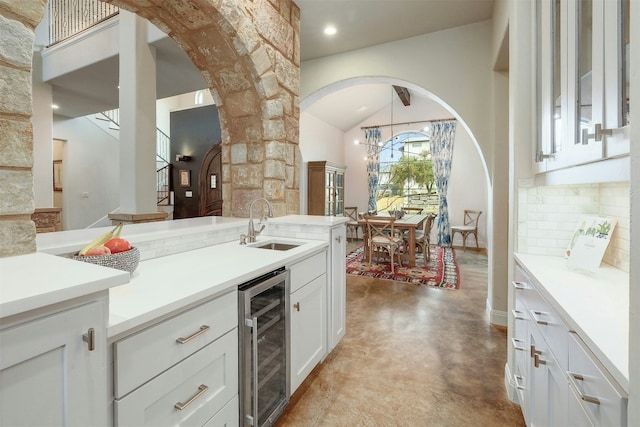 kitchen featuring wine cooler, white cabinets, light countertops, and decorative backsplash