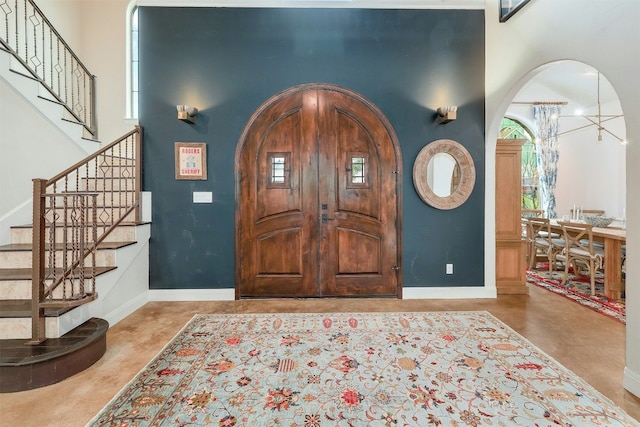 entryway featuring arched walkways, a high ceiling, stairway, and baseboards