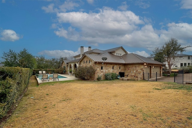 rear view of house with a fenced backyard, metal roof, an attached garage, a standing seam roof, and a yard