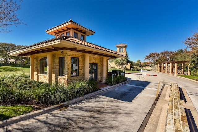 view of home's exterior with stone siding, a tile roof, and driveway