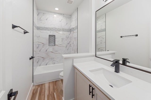 full bathroom with vanity, toilet, tiled shower / bath combo, and hardwood / wood-style floors