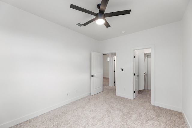 unfurnished bedroom with ceiling fan, a walk in closet, a closet, and light carpet