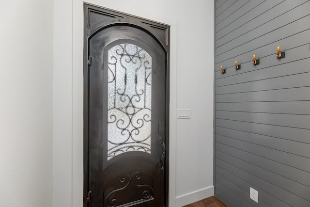 foyer entrance with dark hardwood / wood-style floors and wood walls