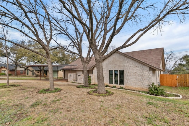 view of front of home with brick siding, a front yard, and fence