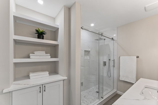 full bathroom with built in features, recessed lighting, a sink, and a marble finish shower