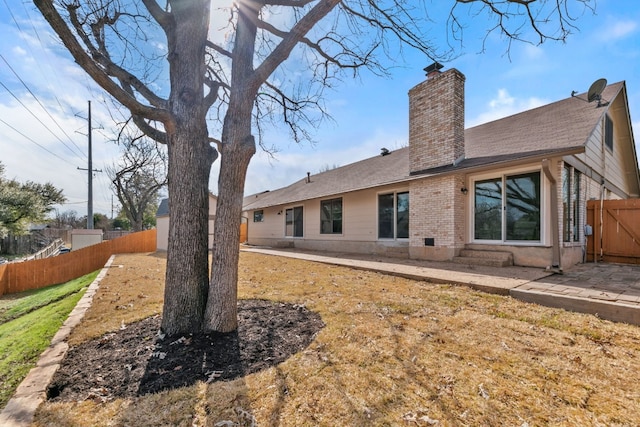 rear view of property featuring a chimney, fence, a patio, and brick siding