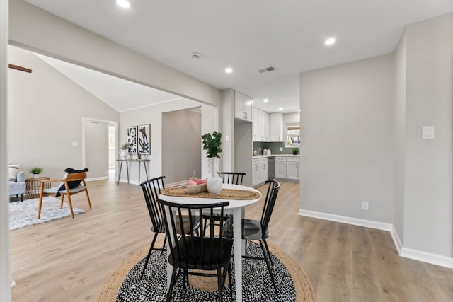 dining space with lofted ceiling and light wood-type flooring