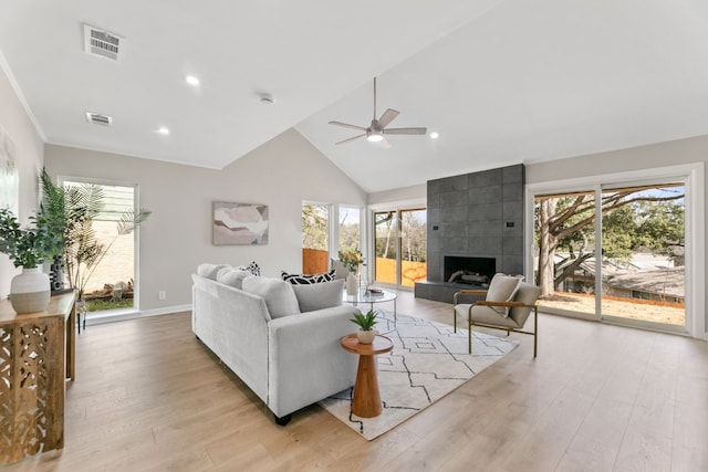 living room with light wood-style flooring, visible vents, and a healthy amount of sunlight