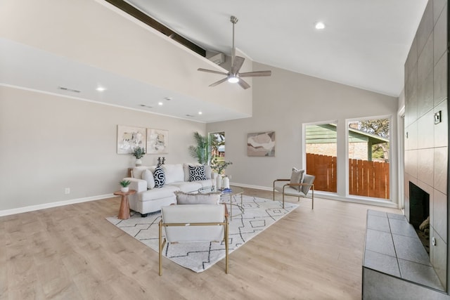 living room featuring high vaulted ceiling, light wood-type flooring, beamed ceiling, ceiling fan, and a fireplace