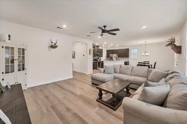 living room featuring ceiling fan with notable chandelier and light wood-type flooring