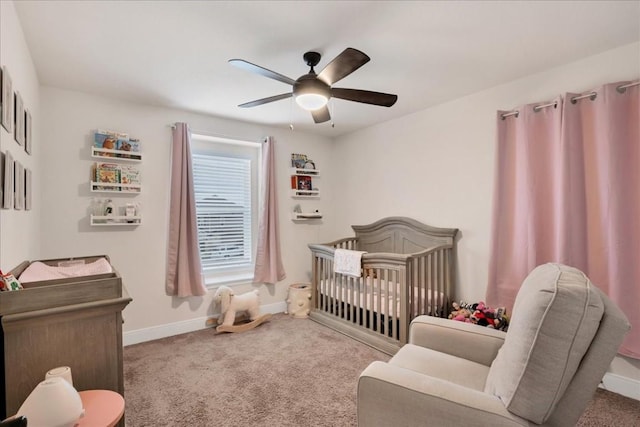 bedroom featuring a nursery area, ceiling fan, and carpet flooring