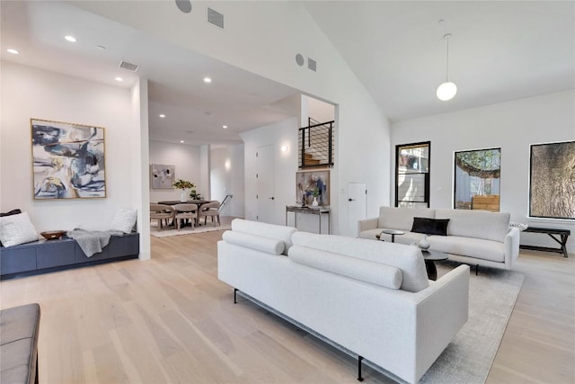 living room with light hardwood / wood-style flooring and high vaulted ceiling