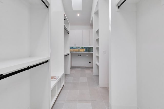 spacious closet with light tile patterned flooring and a skylight