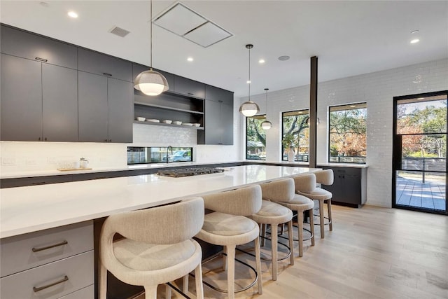 kitchen featuring pendant lighting, a kitchen breakfast bar, light hardwood / wood-style floors, and gray cabinetry